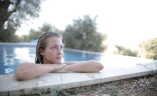 Free A young woman relaxing on the edge of a pool, enjoying a sunny summer day. Stock Photo
