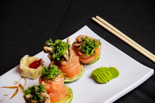 Free A beautifully plated salmon sushi dish garnished with wasabi and served with chopsticks on a white plate. Stock Photo
