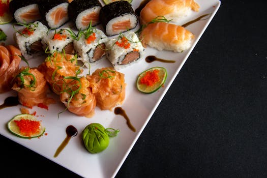 A mouth-watering assortment of sushi including salmon sashimi, maki rolls, and nigiri on a white plate.
