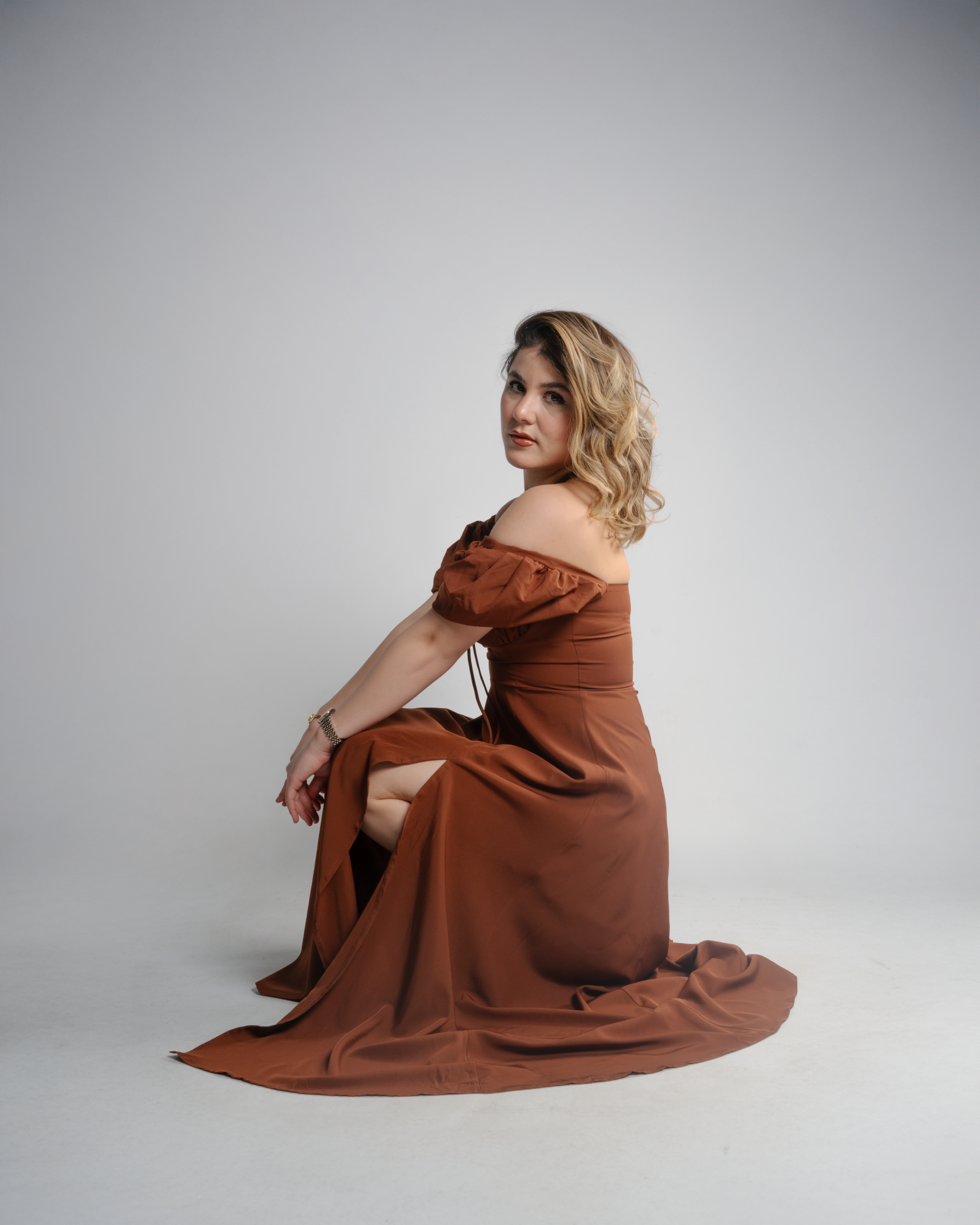 Elegant Woman in Brown Dress Sitting on Studio Floor · Free Stock Photo