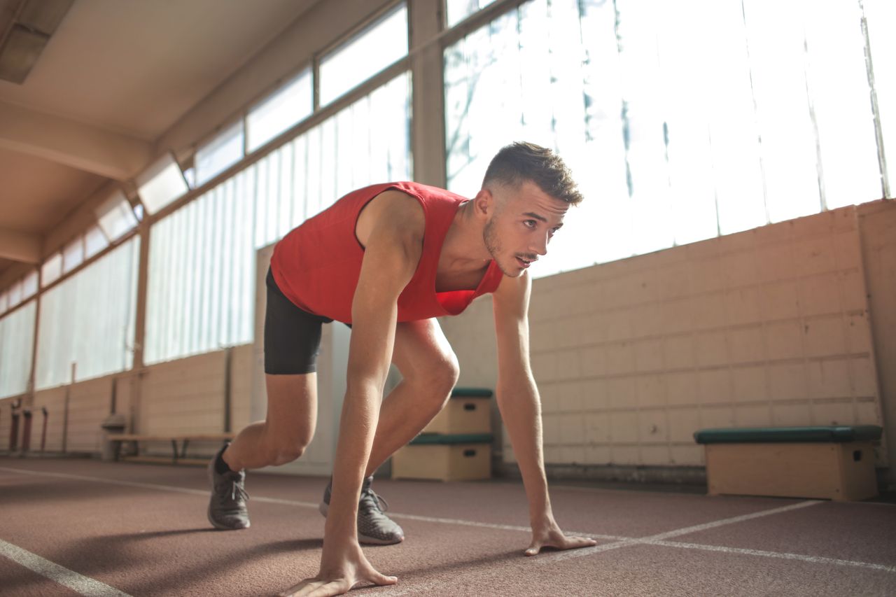 focused male athlete in starting position indoors ready to sprint
