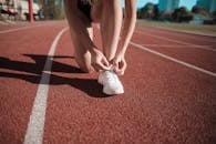 特写镜头：一名女子在跑道上系好鞋带，准备冲刺