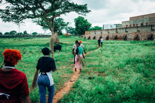 A group of people engaged in community cleaning along a path with greenery in Uganda.