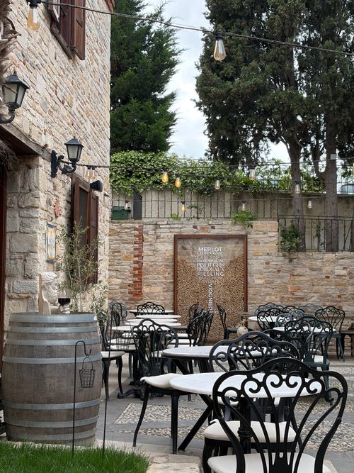 Free A picturesque outdoor cafe setup with vintage tables, stone walls, and ivy in a quaint Turkish setting. Stock Photo