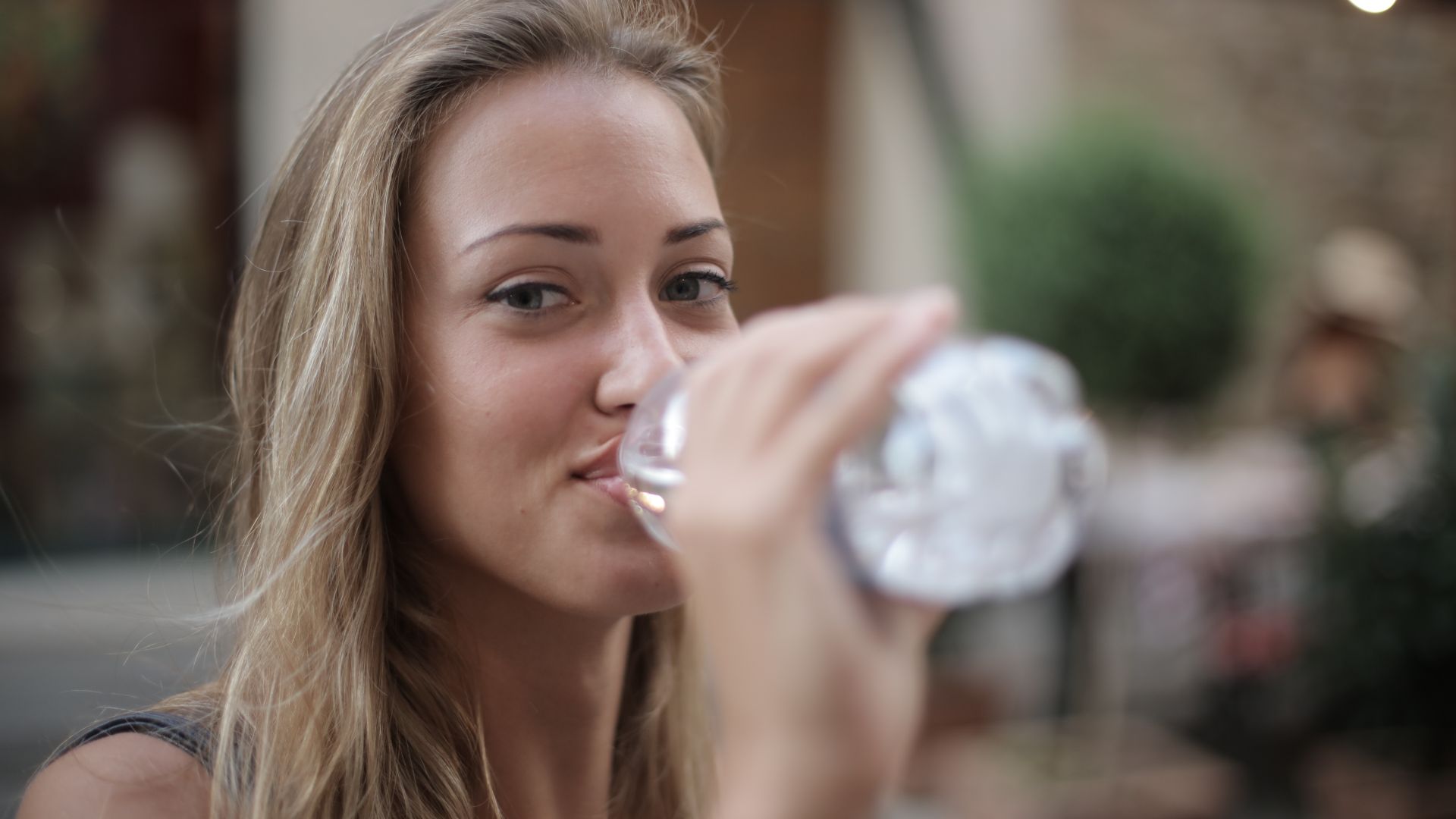 Why Does Modafinil Make You Thirsty: Understanding the Mechanism Portrait of a smiling woman drinking bottled water outdoors, enjoying hydration and relaxation — why does modafinil make you thirsty