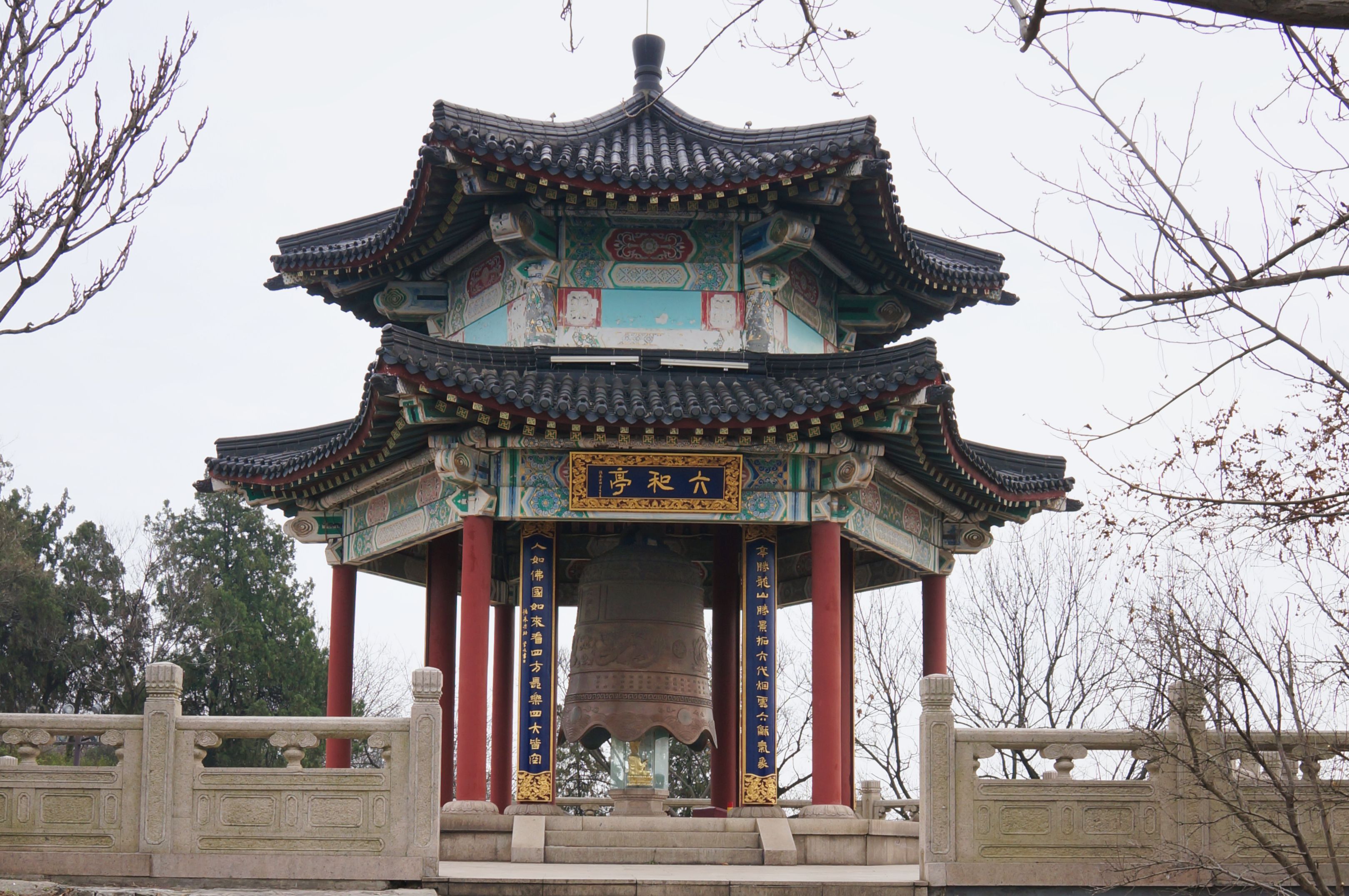 Beautiful traditional Chinese pavilion with ornate architecture and bell, captured in a serene winter setting.