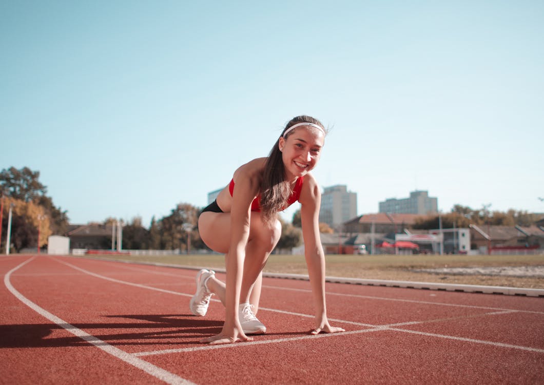 Free Woman in Red Tank Top and Black Shorts Running on Track Field Stock Photo
