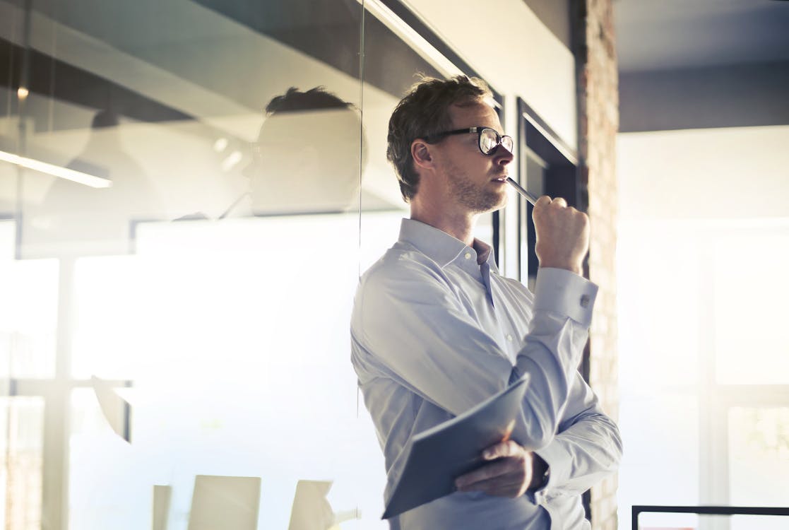 Free Photo of Man in White Dress Shirt and Black Framed Eyeglasses Holding a File Thinking  Stock Photo