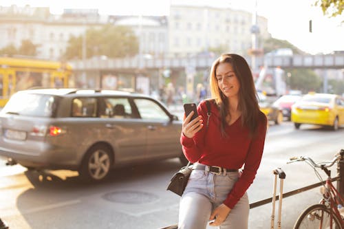 Woman in Red Long Sleeve Shirt and Blue Denim Pants Sitting Metal Realing