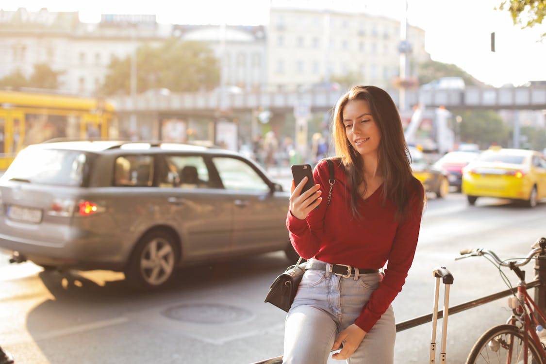 Free Woman in Red Long Sleeve Shirt and Blue Denim Pants Sitting Metal Realing Stock Photo