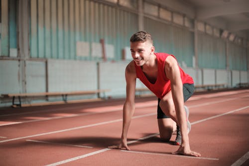 Free Photo of Smiling Man in Active Wear On His Marks on Running Track Stock Photo