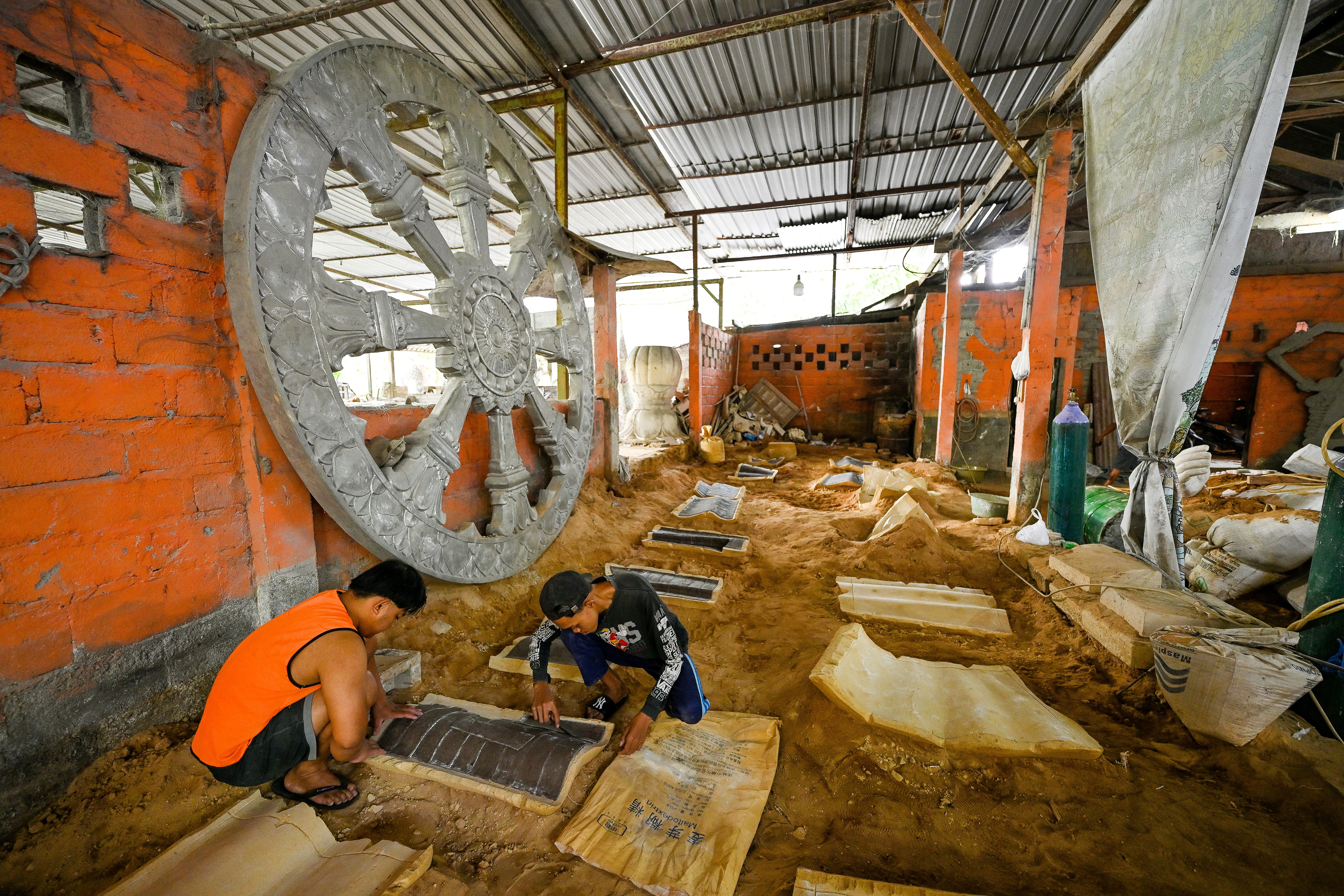 Skilled artisans working in a Magelang workshop creating intricate sculptures.