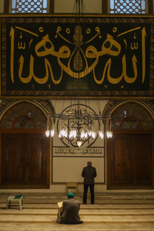 Free Two worshippers inside the historic Ulu Cami Mosque in Bursa, Türkiye, emphasizing architectural grandeur. Stock Photo