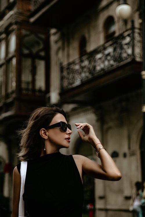 Free Elegant woman wearing sunglasses poses against historic architecture in Baku, Azerbaijan. Stock Photo