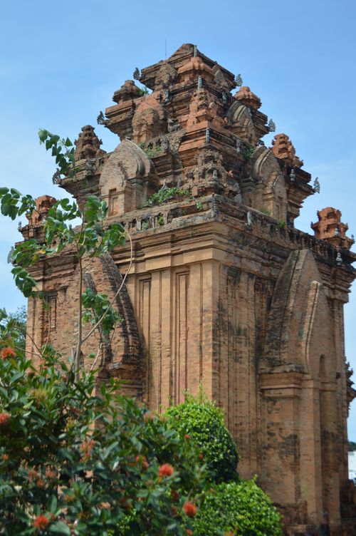 Free Historic Cham temple tower with intricate carvings surrounded by vibrant greenery under a clear blue sky. Stock Photo