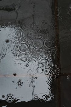 Abstract view of rain creating ripples on a reflective surface, evoke the calmness of a rainy day.