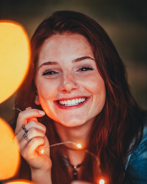 Free  Portrait Photo of Smiling Woman Holding Yellow String Lights Stock Photo