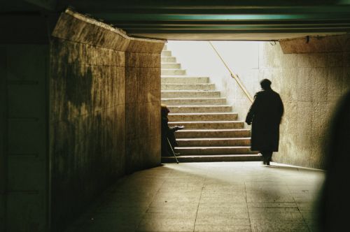 Free Shadowy figures in an urban underpass with light streaming in from the stairs above. Stock Photo