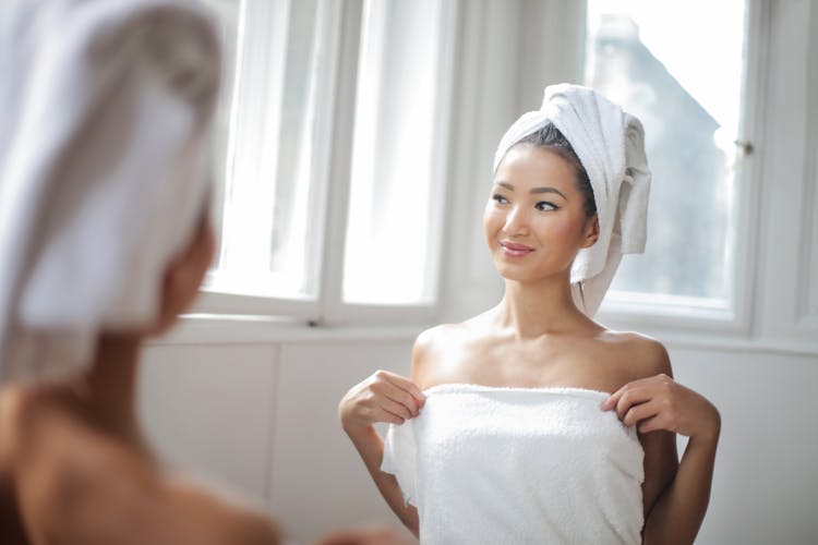 Woman In White Towel Standing In Front Of The Mirror