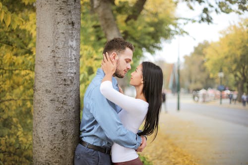 Free Selective Focus Photo of Hugging Couple Looking at Each Other While Standing Next to a Tree Stock Photo
