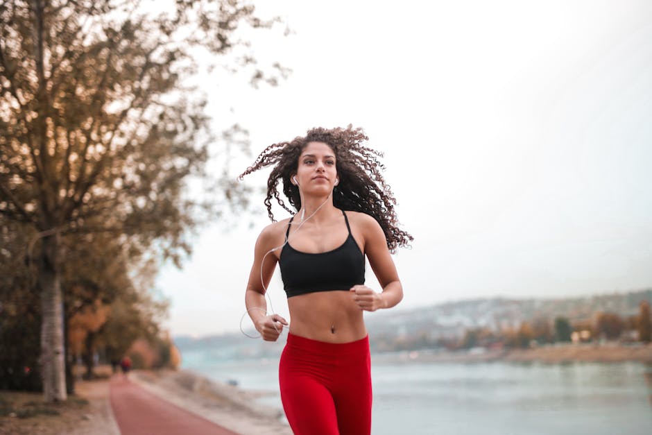 Challenge Ideas for Coaches and Online Creators in 2025 5 Determined woman in red leggings jogging along a scenic riverside path, embracing fitness outdoors.