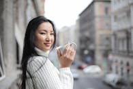 一个穿着针织毛衣的女人在城市背景下享受着一杯咖啡