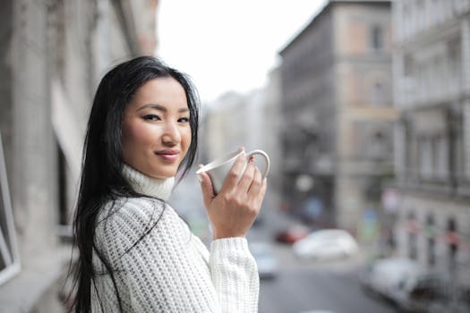 一名女子穿着针织衫，在城市背景下喝着咖啡