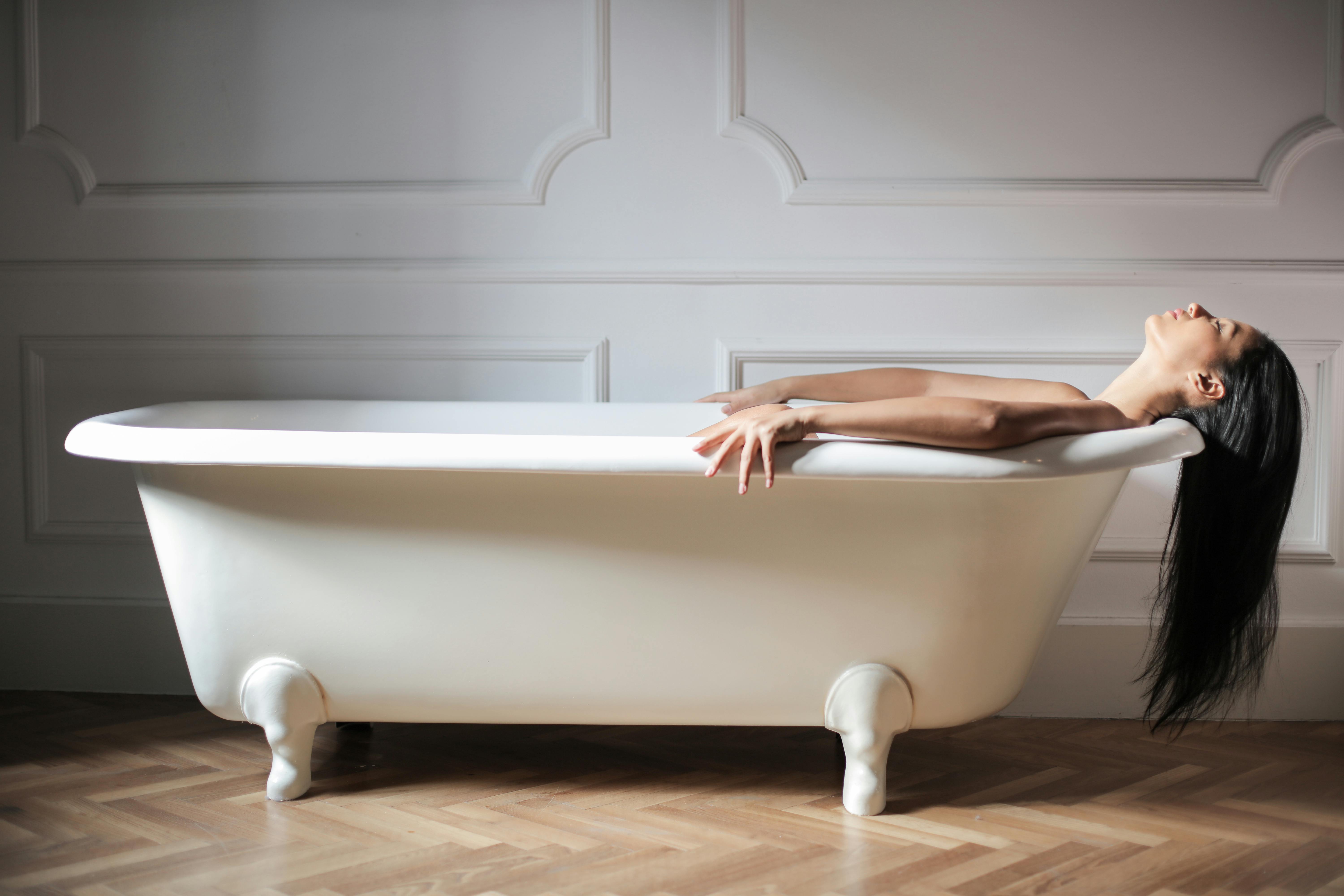 woman lying on a white bathtub