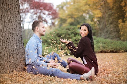 無料 幸せなカップルが公園で葉を散乱 写真素材