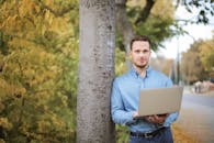 一名男子在公园的户外使用笔记本电脑，拥抱数字游牧的生活方式