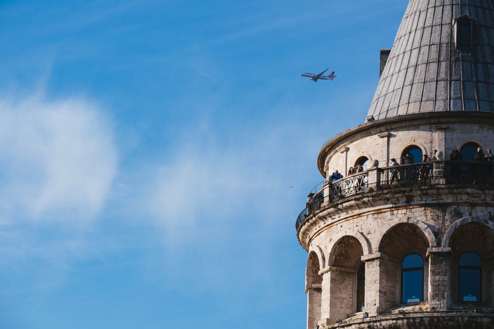 Torre de Gálata en Estambul con un avión sobrevolando el cielo despejado