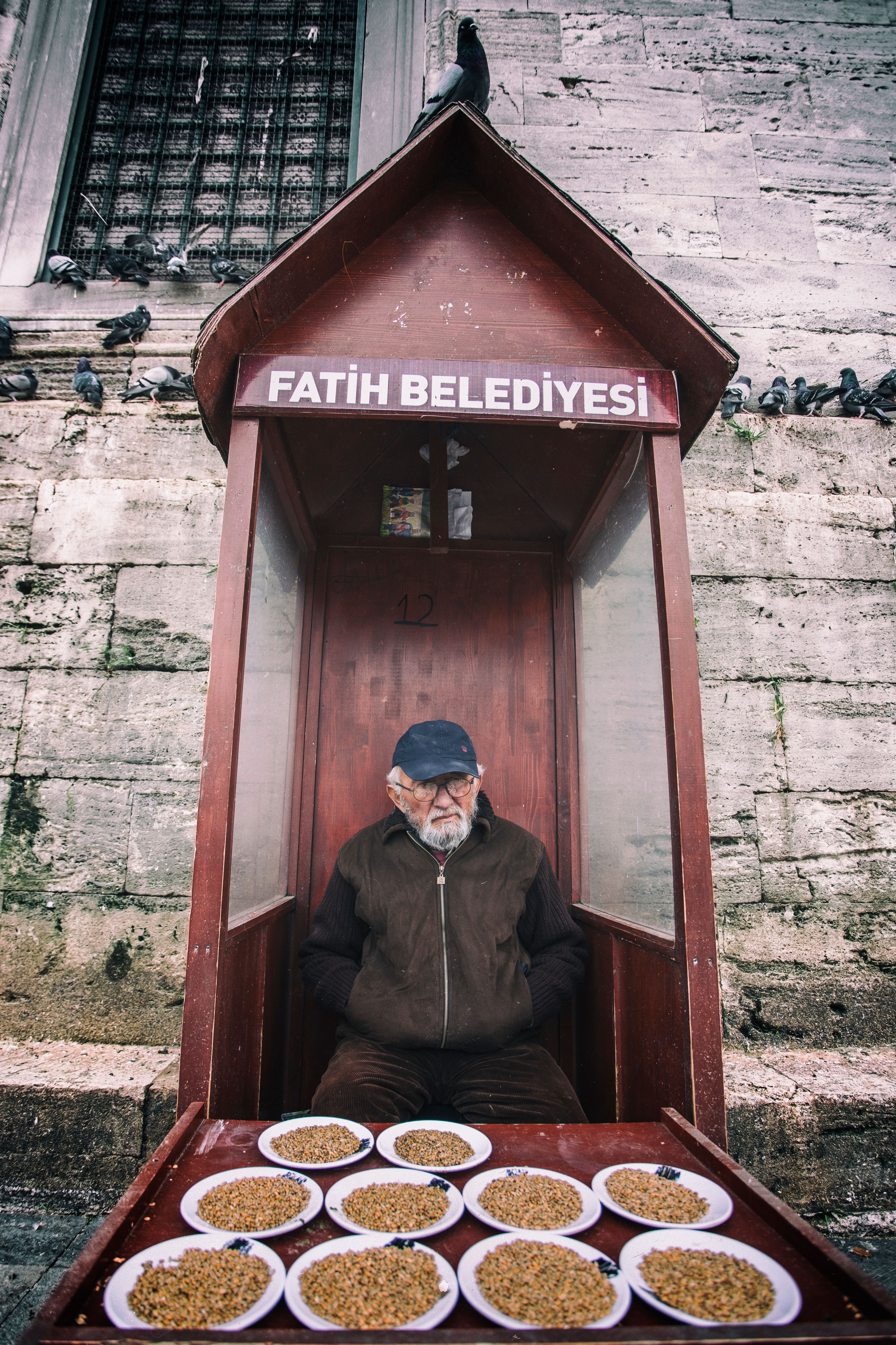 An elderly man in a booth feeding pigeons at Eminönü, İstanbul.