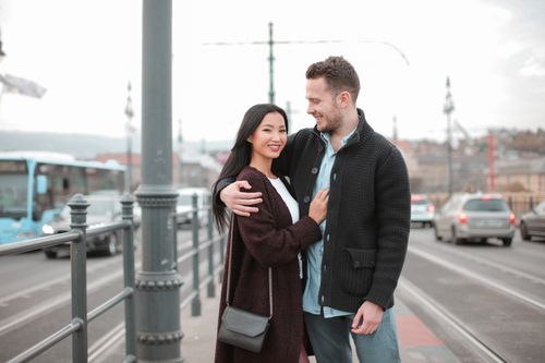 Free Smiling couple embracing on a bustling city bridge, conveying love and togetherness. Stock Photo