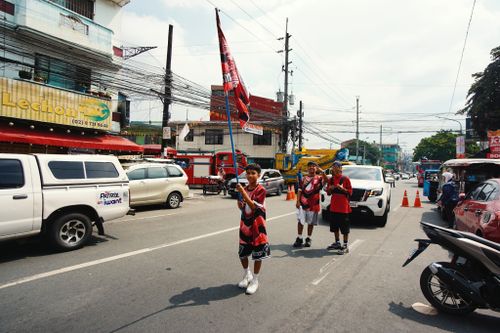 Free A lively parade features people carrying flags on a bustling city street. Stock Photo