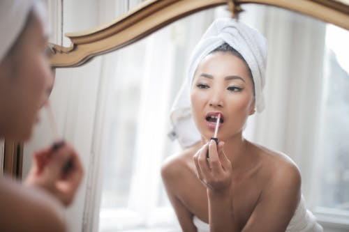 Topless Woman Putting Lipstick on Her lips