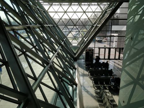 Free A spacious airport terminal with modern geometric glass panels and rows of waiting chairs. Stock Photo