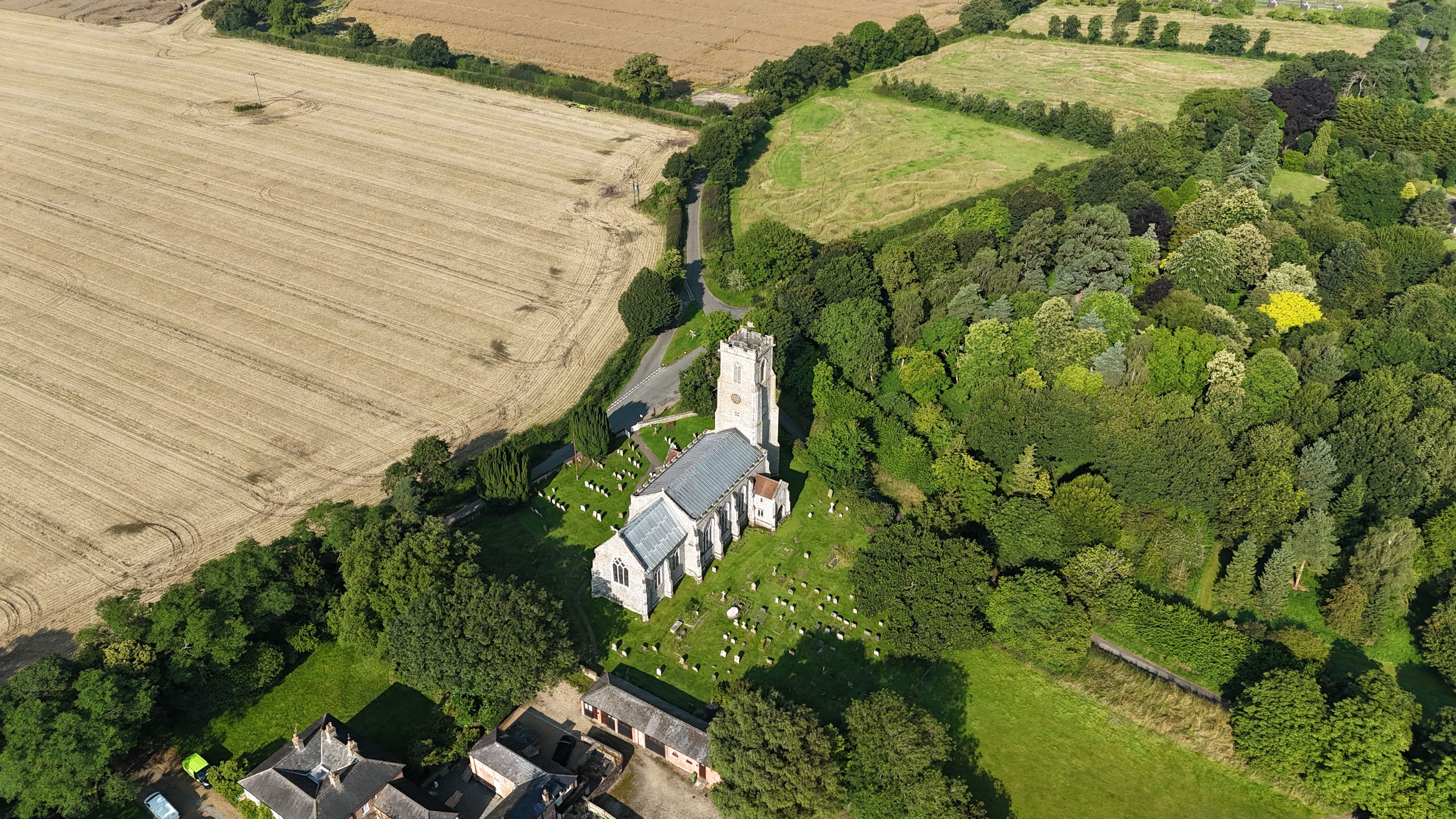Aerial photograph of a rural church surrounded by fields and trees in Ludham, Norfolk, England.