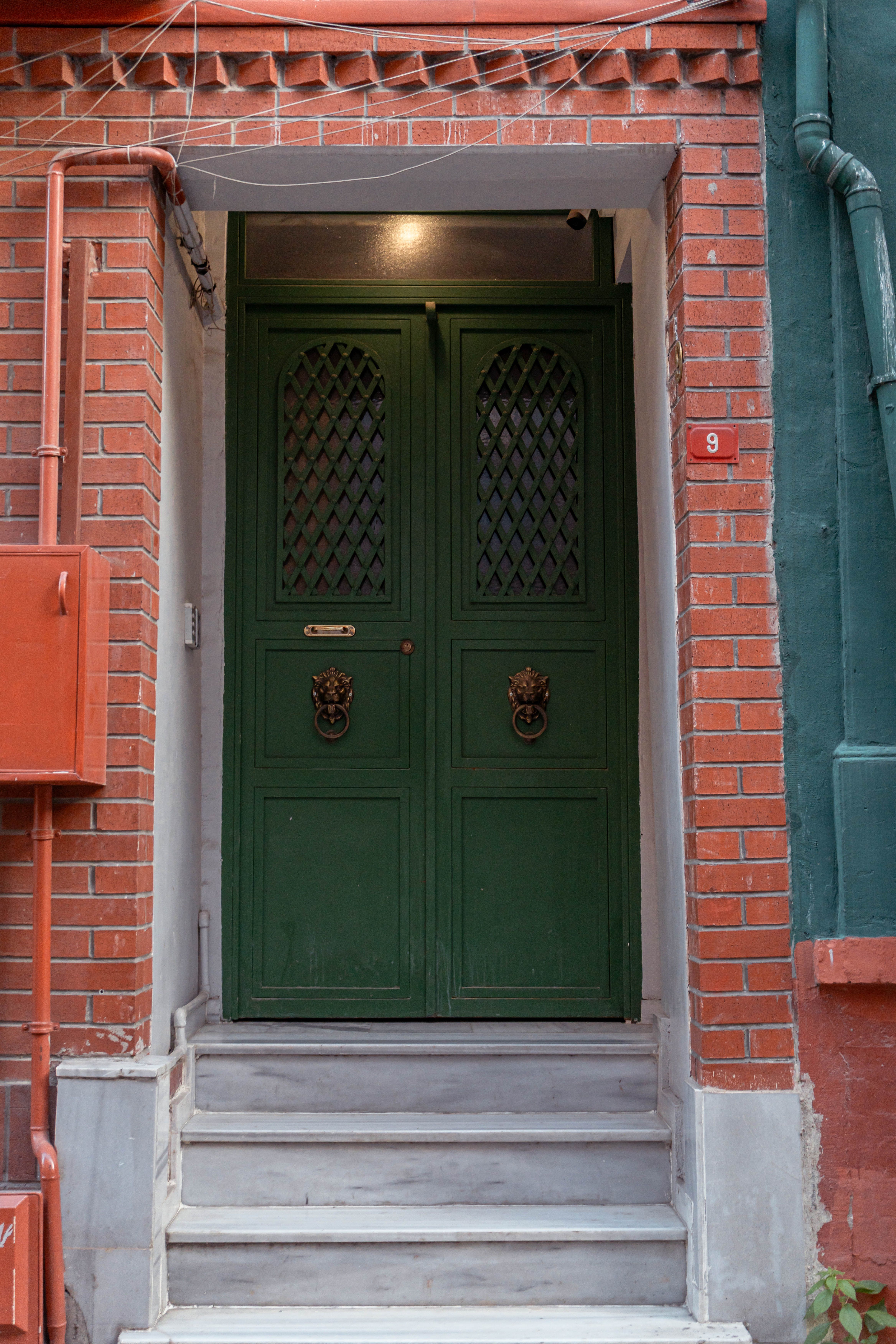 A vintage green door set in a red brick facade in Istanbul, Türkiye, exuding historic charm.
