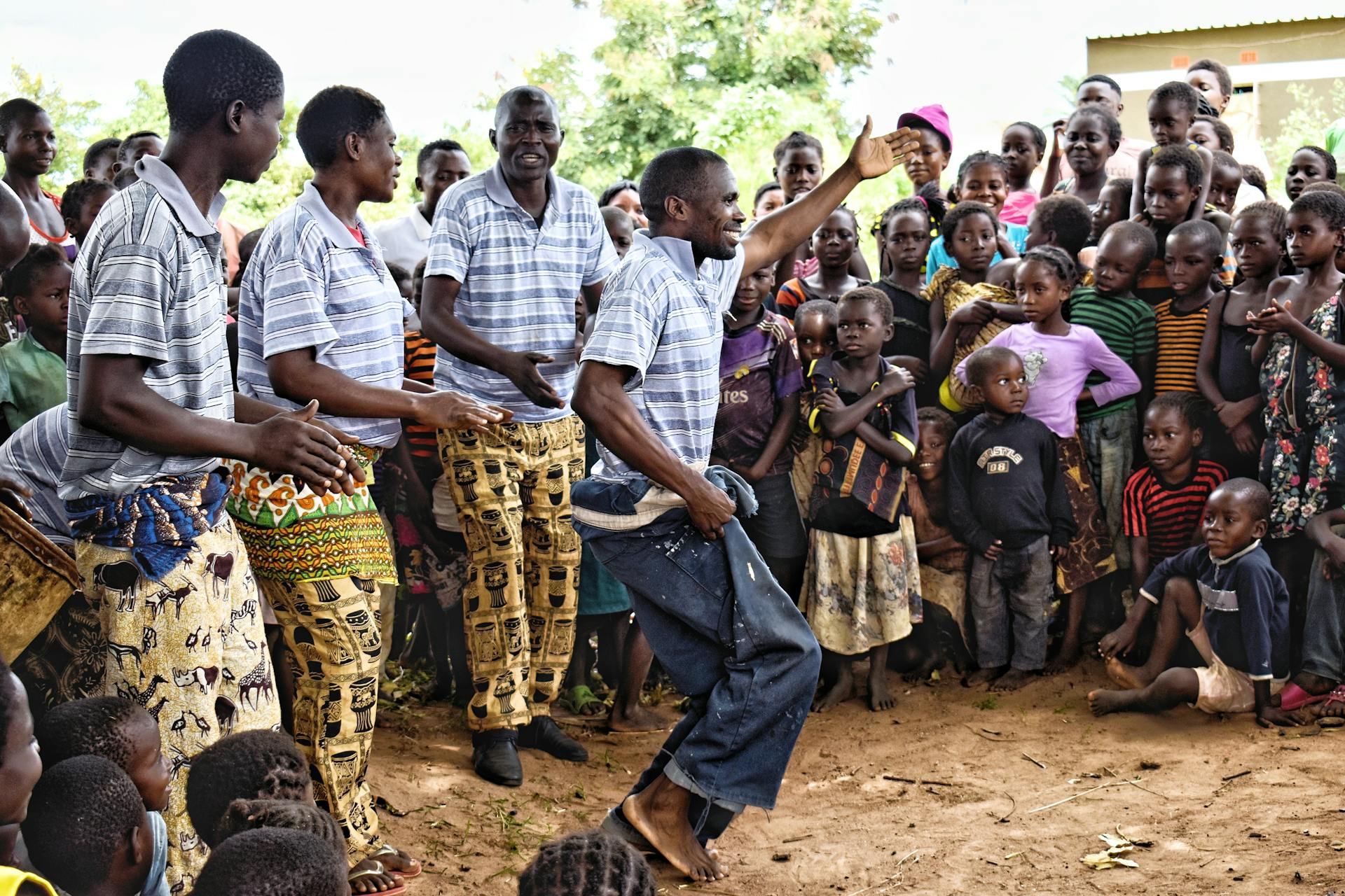 African community members enjoying a traditional dance performance outdoors, showcasing cultural unity and joy.