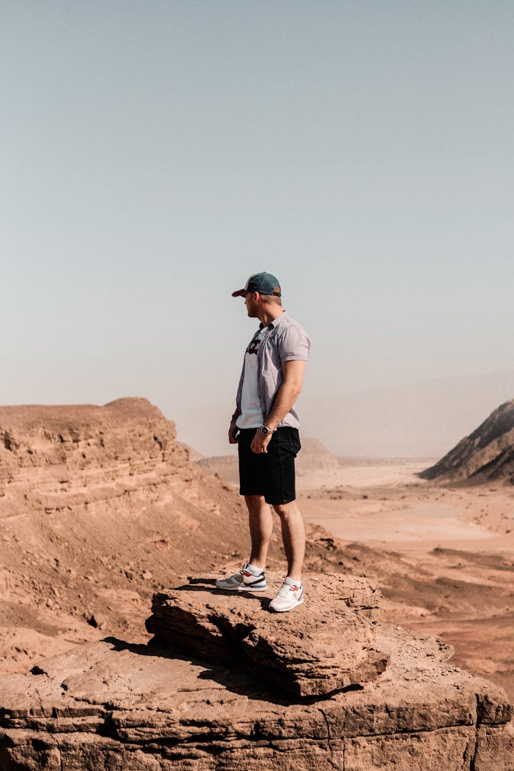 Man Standing On A Brown Rock Formation