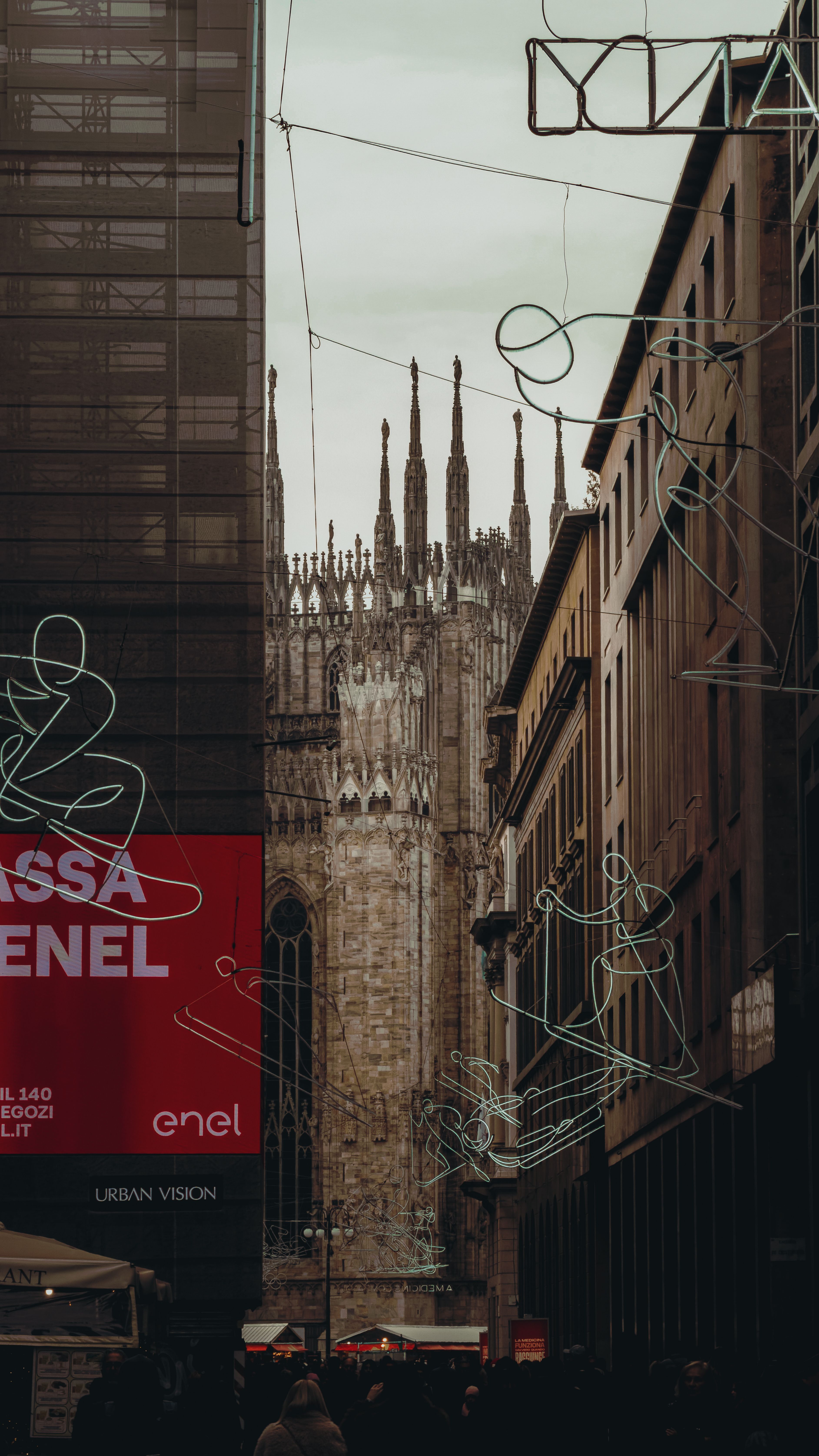 Dramatic urban scene with Milan Cathedral in the background, captured from a busy street with neon art installations.