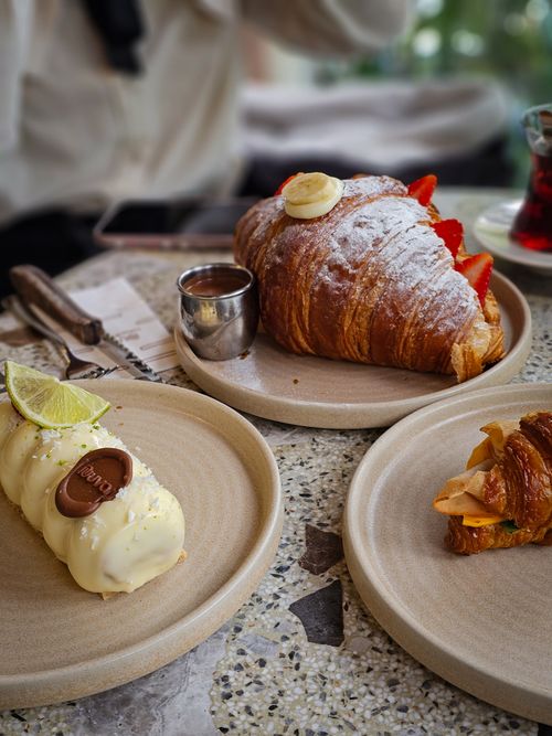 Free Delicious croissants and desserts served on a textured café table, perfect for pastry lovers. Stock Photo