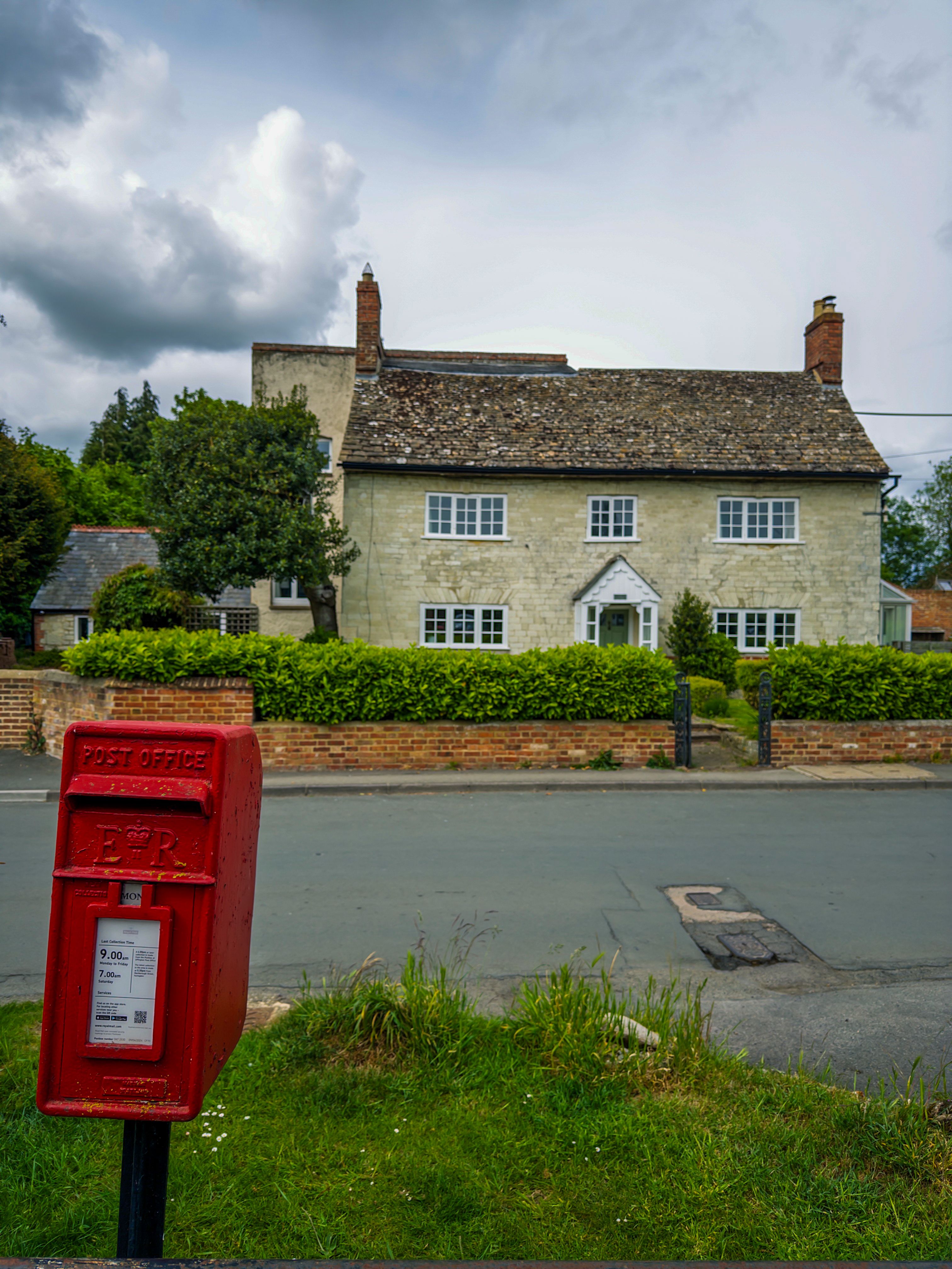 Charming English cottage with a traditional red post box, perfect for travel and architecture themes.