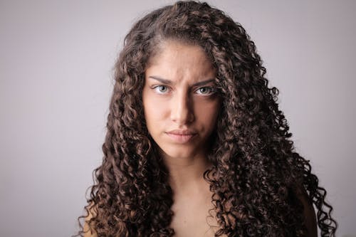 Free Portrait Photo of Unamused Woman With Brown Curly Hair Stock Photo