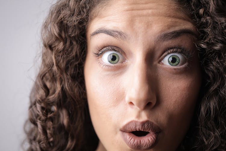 Close-up Photo Of Shocked Woman With Brown Curly Hair