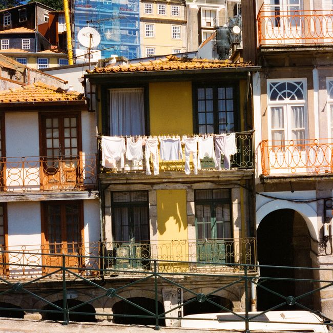 Colorful Porto apartments with traditional iron balconies and laundry drying in the summer sun.