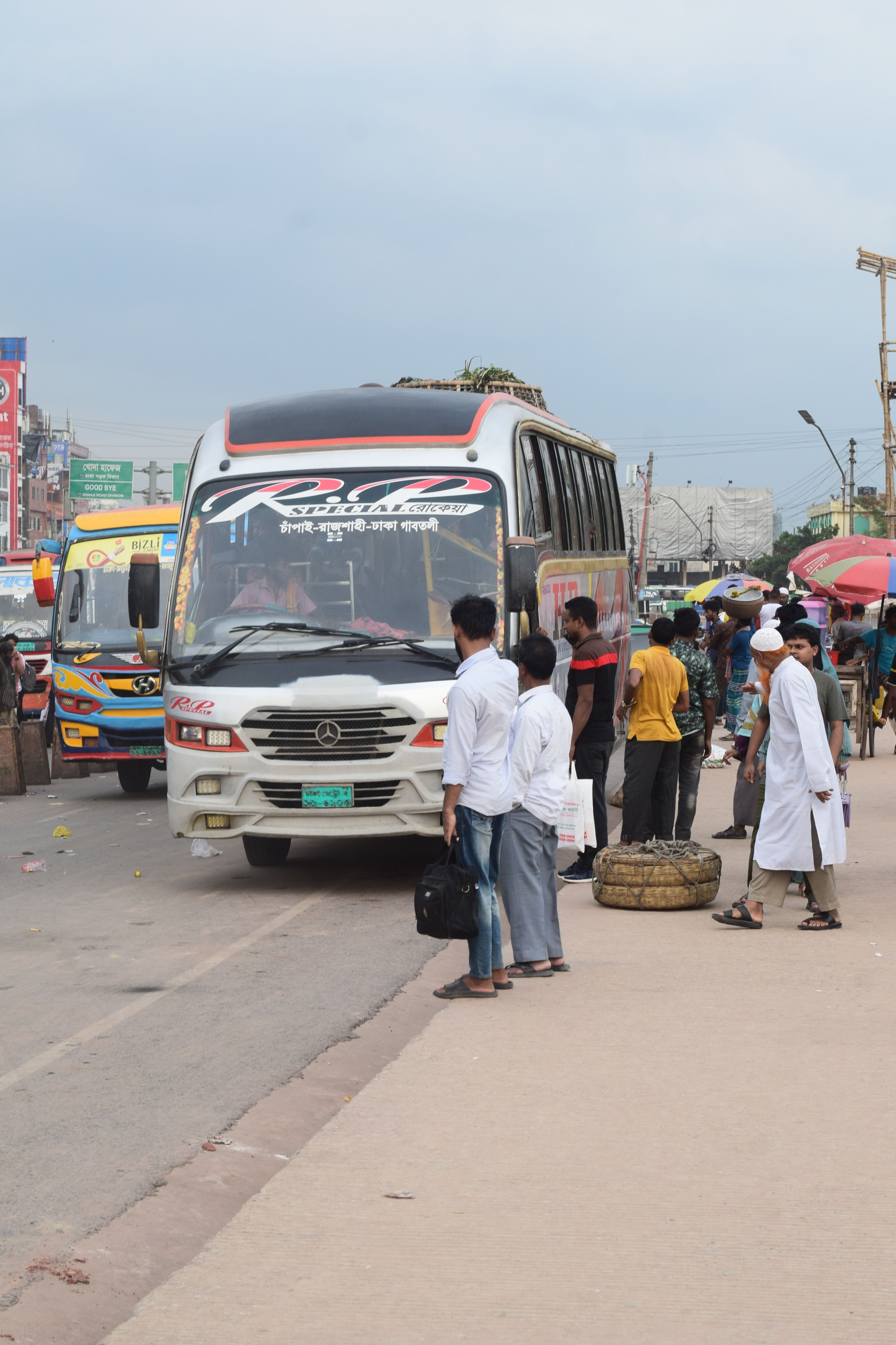 People boarding a bus at a lively street in Aminbazar, Dhaka Division, Bangladesh.