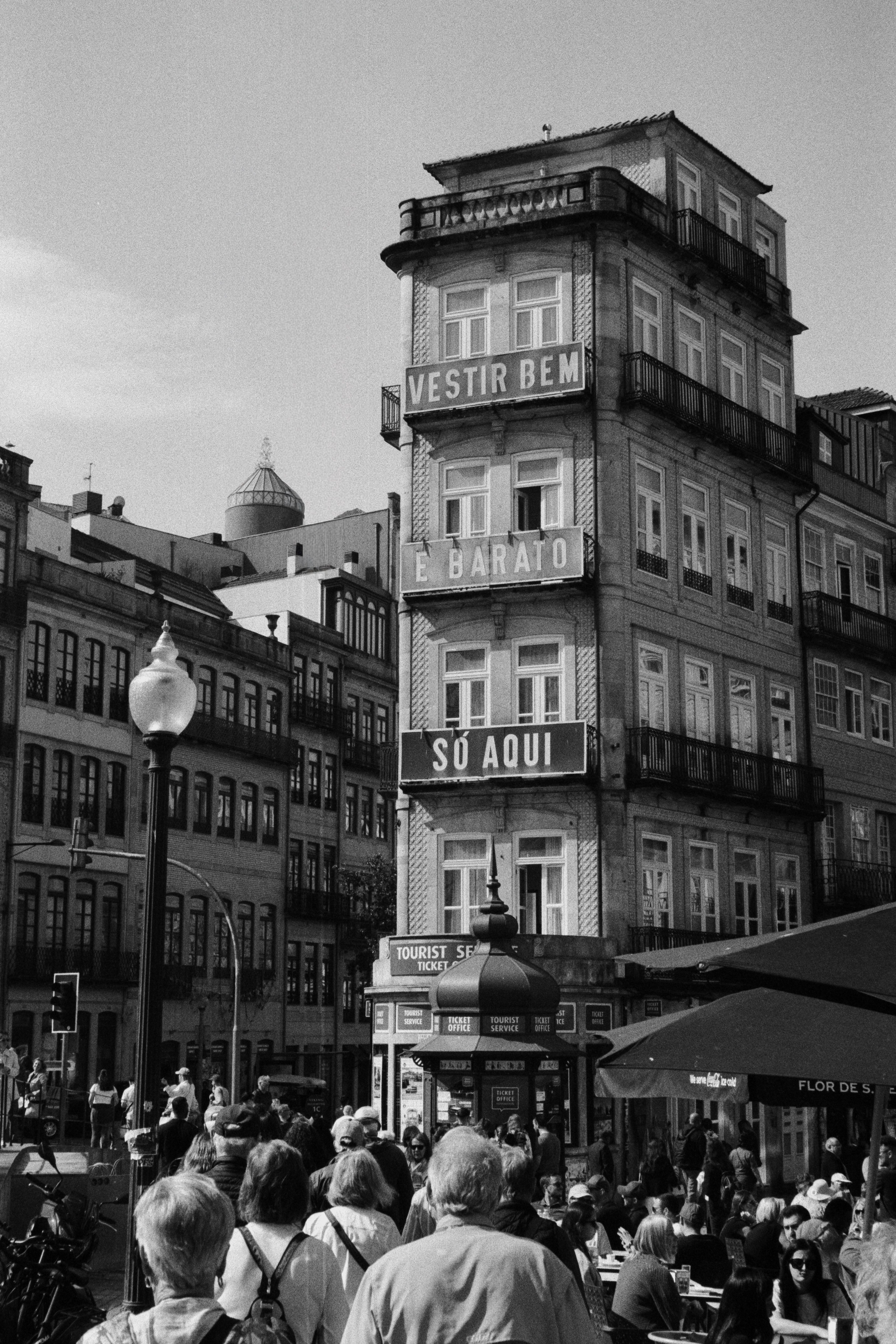 Black and white photo of a historic city building with bustling crowd in foreground.