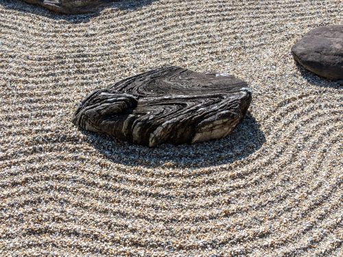 Free Close-up of a patterned rock in a Zen garden with raked gravel, creating a tranquil atmosphere. Stock Photo