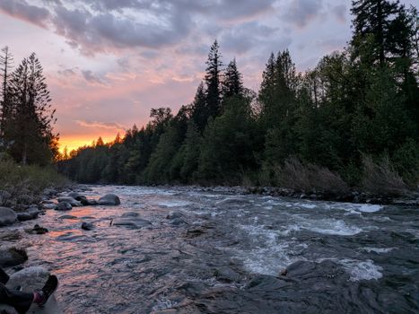 Beautiful sunset over a forest river in Oregon, capturing the vibrant colors of nature.